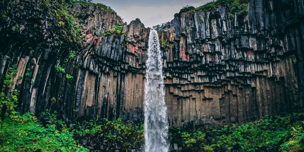 Subcategoría hidrogeología e hidrología: cataratas que caen de una formación rocosa de basaltos columnares en Islandia.